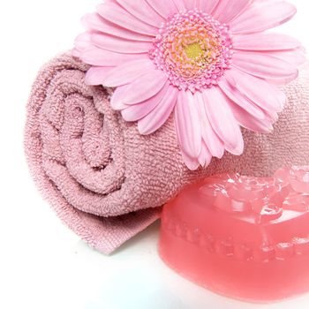 a pink towel and a pink soap with a flower