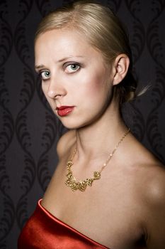 elegant blonde woman wearing golden necklace, over wallpaper background