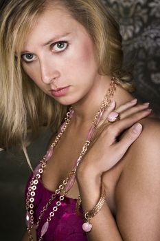 elegant woman wearing golden necklace and bracelet, over wallpaper background