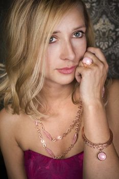 elegant woman wearing golden necklace and bracelet, over wallpaper background
