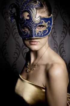 atractive woman in gold blue mask over wallpaper background