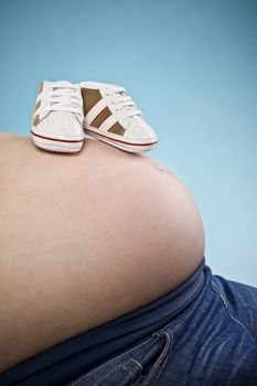 pregnant female with shoes on belly over vivid backround