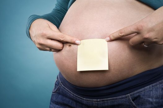 pregnant female pointing at notepaper on her belly