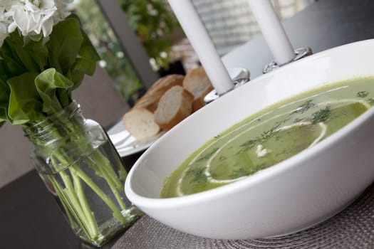 Fresh pea soup with cream and fresh dill on dark table.