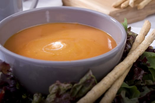 Homemade tomato soup with bread sticks, salad greens and a dollop of cream.  