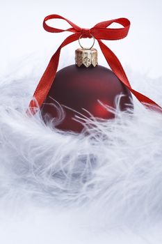 christms ball with decorative red ribbon on feather