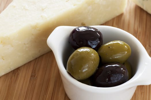 Small dish of green and black olives with wedge of Parmesan cheese