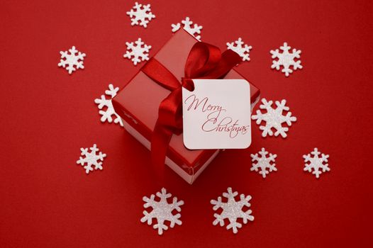 christmas gift with decorative red ribbon on red background