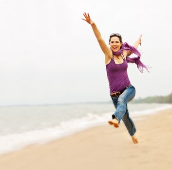 A beautiful energetic young woman taking a great leap on the beach