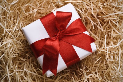 christmas gift with red ribbon on hay background