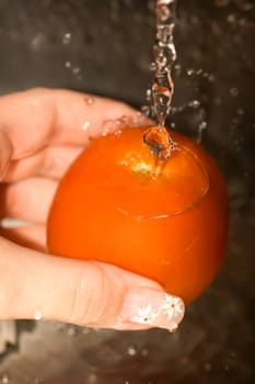 Washing tomatoes -  A girls hand holding tomato under the tap