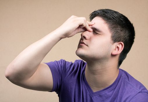 Young man has an intense headache. He might be experiencing stress during a time of economic crisis or other hardship.