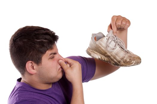 A teenager pinches his nostrils closed over the odor given off from the athletic shoe he is holding.