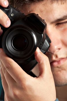 A young teenage photographer taking a photo with his DSLR camera. Shallow depth of field.