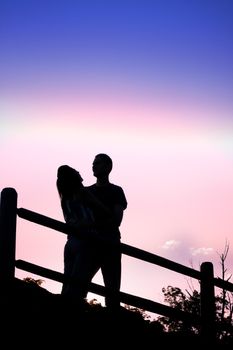 Silhouette of an affectionate couple romantically kissing each other in the early evening hours.