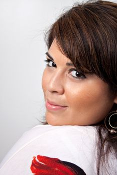 A beautiful young Hispanic woman with a smile on her face isolated over a silver background.