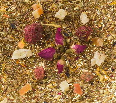 Background image consisting of tea leaves and dry fruits with focus on berries