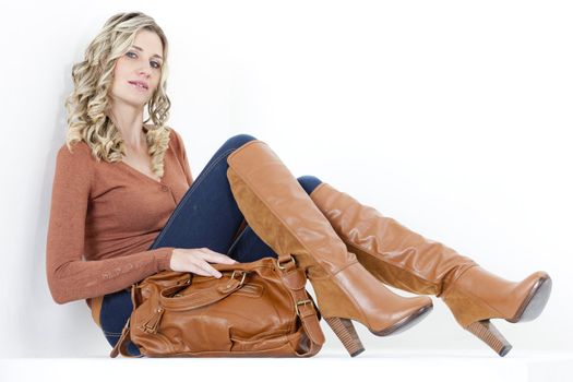 sitting woman wearing fashionable brown boots with a handbag