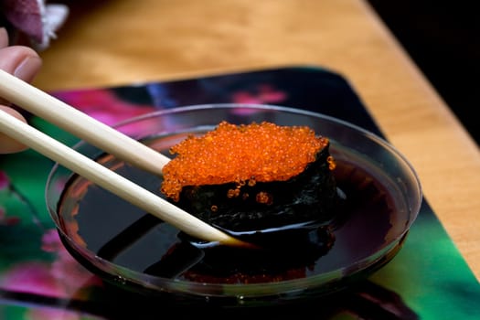 sushi with red roe tken with chopsticks