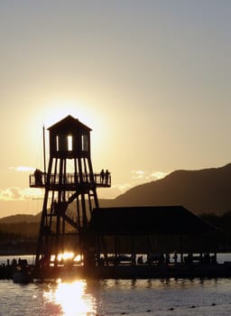 Observation tower in silhouette at sunset on Memphremagog lake, province of Quebec, Canada, with Mont-Orford in background