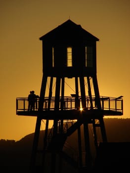 Observation tower in silhouette at sunset on Memphremagog lake in Magog, province of Quebec, Canada, with Mont-Orford in background
