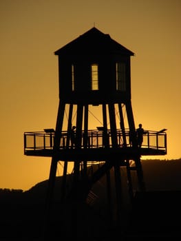 Observation tower in silhouette at sunset on Memphremagog lake in Magog, province of Quebec, Canada, with Mont-Orford in background