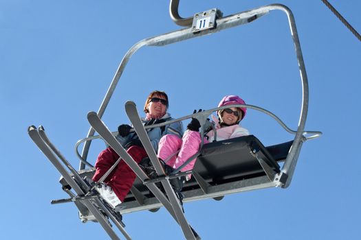 Two women fly high on the ski lift.