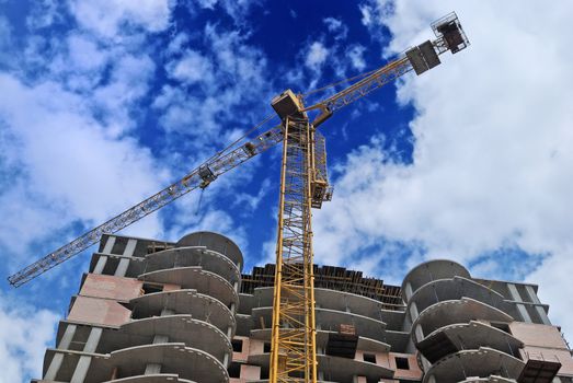 building construction with yellow crane on blue sky