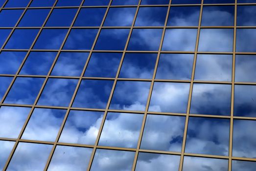 a mirror reflection of sky and clouds is in the windows of building