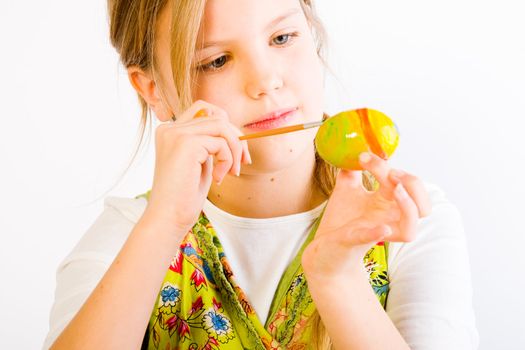 Studio portrait of a young blond girl who is painting eggs for easter