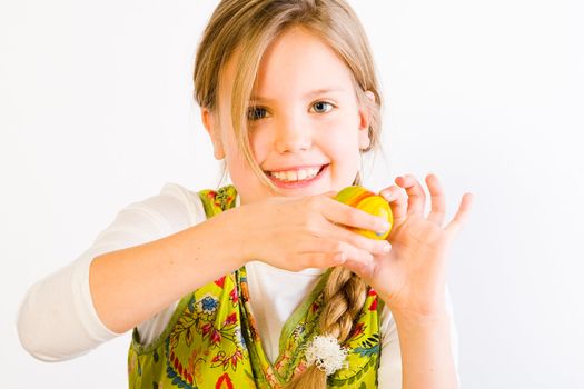 Studio portrait of a young blond girl who is presenting her painted easter egg