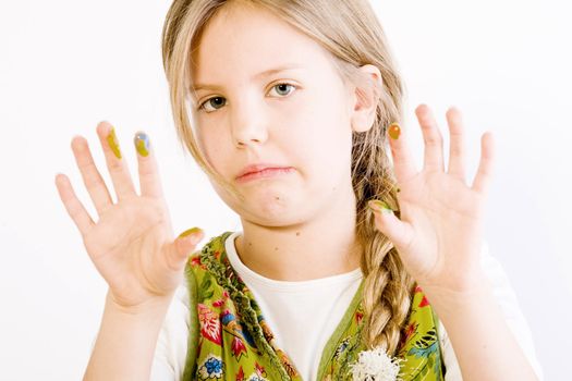 Studio portrait of a young blond girl showing her hands smudged with paint