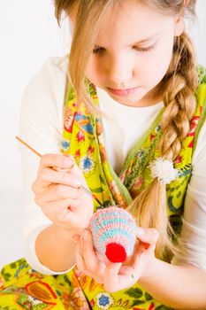 Studio portrait of a young blond girl who is painting eggs for easter