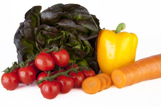 Fresh yellow pepper, lettuce, tomatoes and carrots on white background.