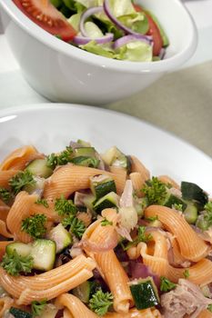 Gigli pasta with fish and zucchini, side salad in background