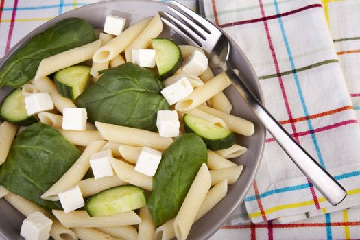 Penne pasta salad with spinach, cucumber and feta cheese.