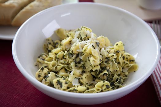 Perline pasta with pesto sauce in white bowl.
