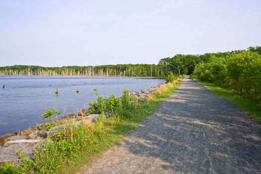The shoreline of a reservoir or lake with a gravel road at the border