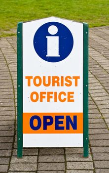 A sign indicating that a tourist office is open. The symbol for information is also shown on the sign.
