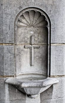 A cross and holy water well as part of the architecture in a cathedral