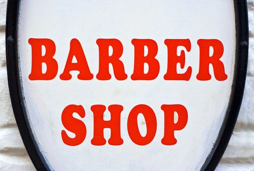 A Barber Shop sign with red letters and a white background