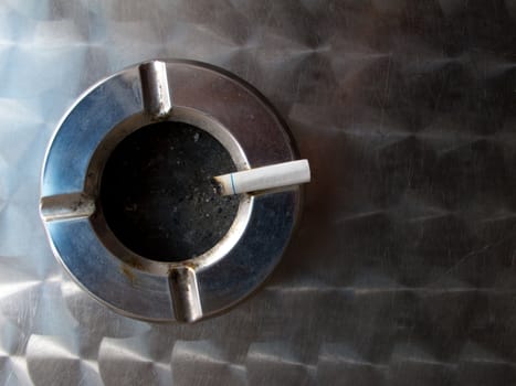 An ash tray on a metal table.