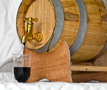 Pouring up a glass of nocino, from a barrel