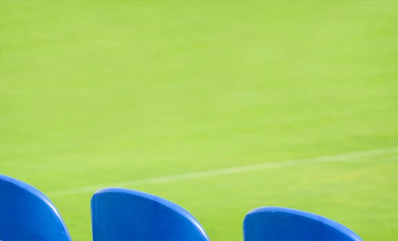 Blue seats and green grass on a footbal stadium