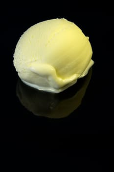 Vanilla ice cream scoop on dark reflective background