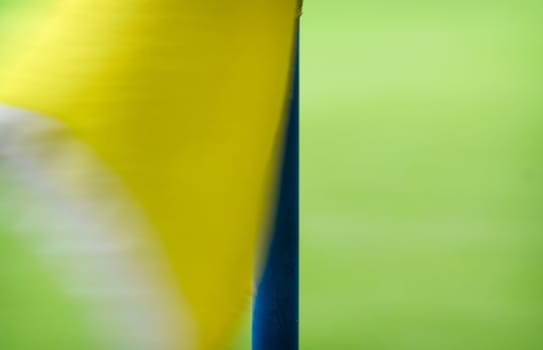 Yellow corner flag on a football field waving in the wind.