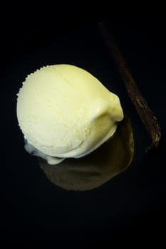 Vanilla ice cream scoop on dark reflective background