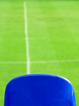Blue seat and green grass on a soccer stadium