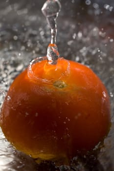 Washing fresh red tomato under water