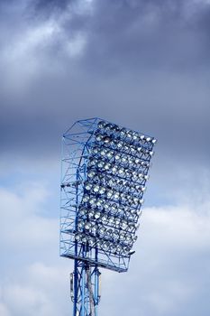 Stadium lights and speakers against blue cloudy sky